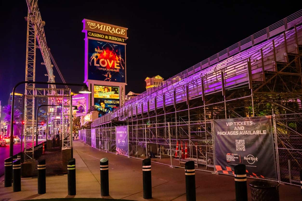 Mirage Casino In Las Vegas Lit Up At Night With Grandstands Set Up For The Upcoming F1 Race Las Vegas, Promoting Vip Tickets And Packages For The Event.